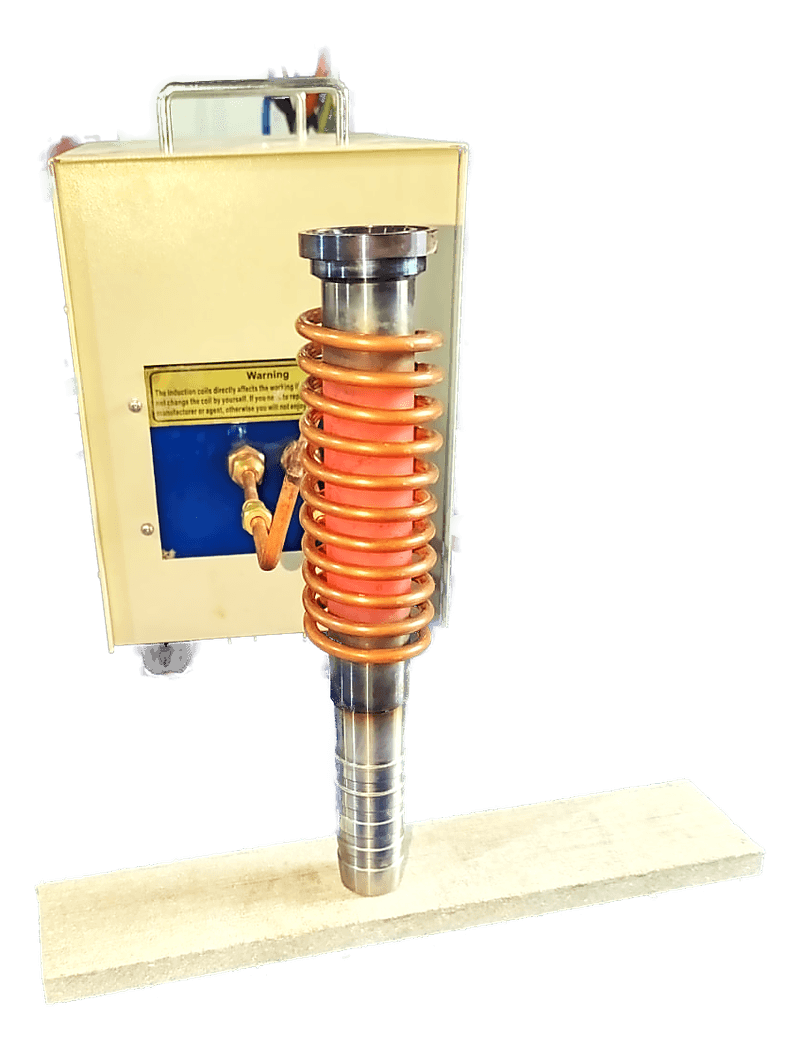 A vertical induction coil with orange refractory packing between the turns, mounted above a blue machine table.