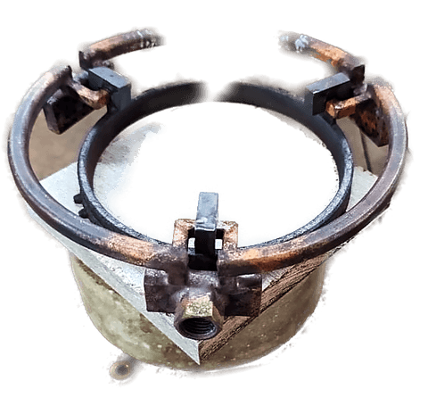 An induction coil clamped inside a machine head, viewed from above, with locating clamps around the workpiece position.