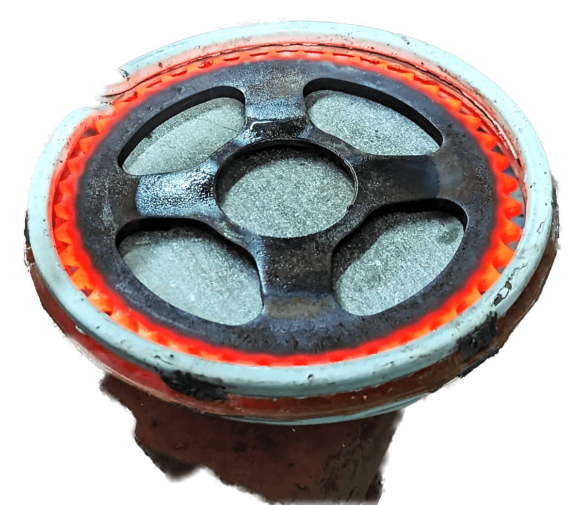 A cast iron ring gear glowing orange around its full circumference inside a circular induction coil, mounted on its fixture.