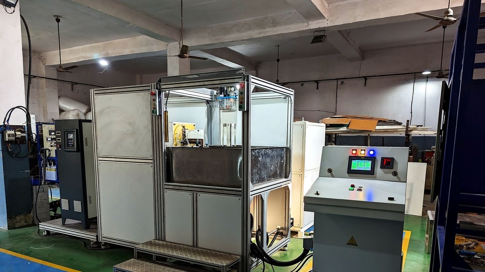 The ABE-120AB flywheel ring hardening machine: a large guarded cell with an aluminium profile frame, touchscreen control station and operator access steps, on our shop floor.